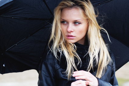 Jeune femme blonde sous la pluie avec un parapluie